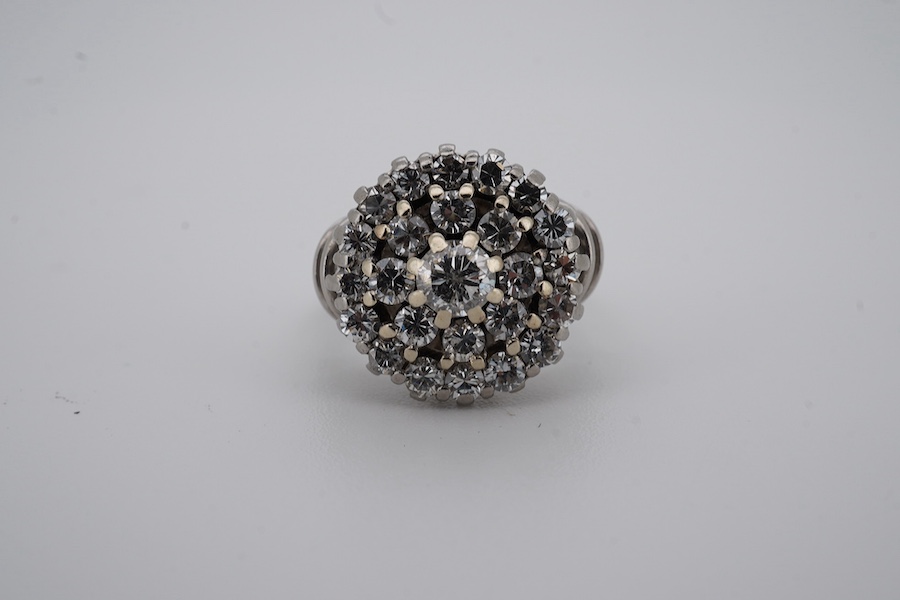 A white metal and diamond cluster set dress ring, with 'wire work' shoulders, size H, gross weight 5.2 grams. Condition - fair to good